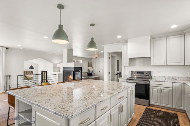 kitchen featuring light wood finished floors, electric stove, light stone counters, and a kitchen island