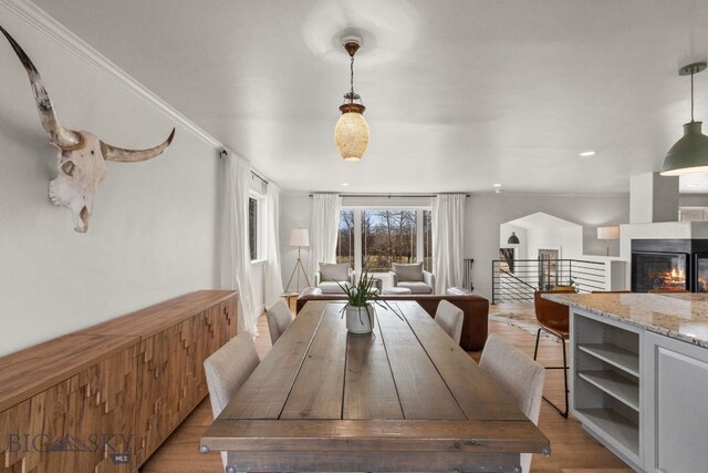 dining area with light wood finished floors, a multi sided fireplace, and recessed lighting