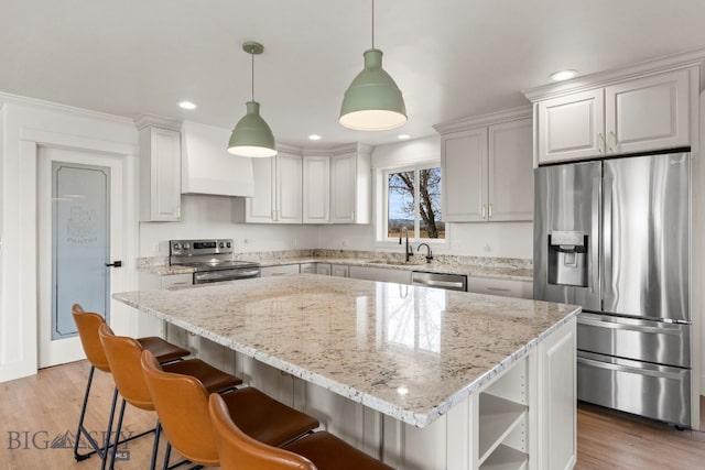 kitchen featuring stainless steel appliances, light wood-style flooring, premium range hood, and a sink