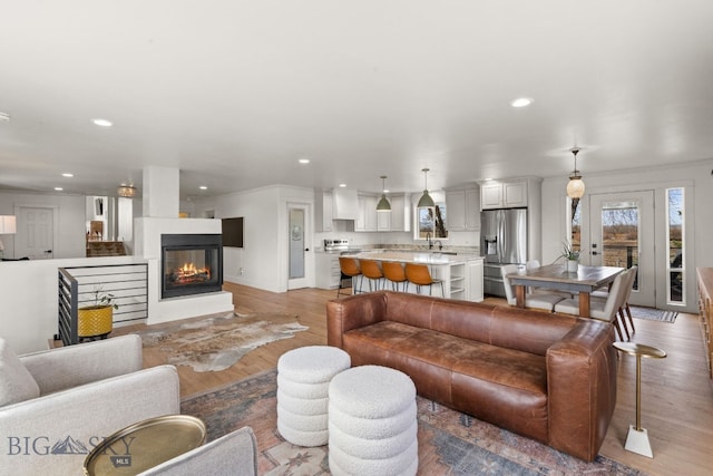 living area featuring recessed lighting, light wood-style floors, and a multi sided fireplace