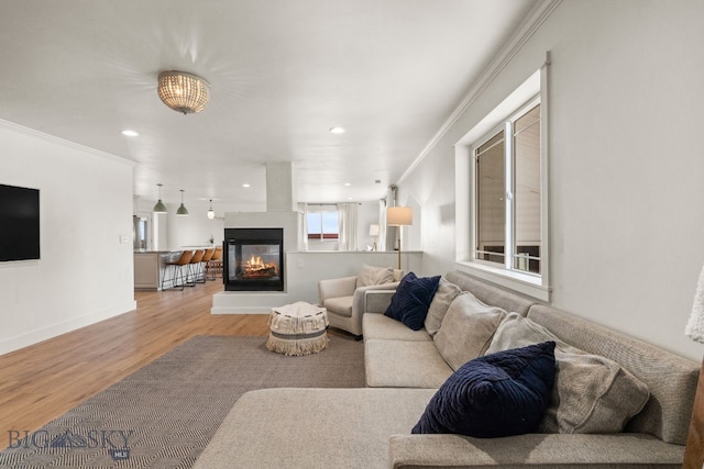 living area featuring light wood-style flooring, baseboards, a multi sided fireplace, and crown molding