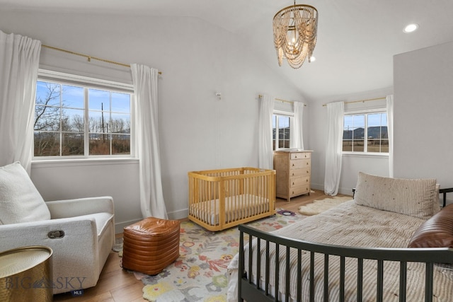 bedroom with light wood-style flooring, a chandelier, baseboards, and lofted ceiling