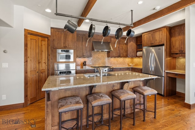 2430 Two Gun White Calf Rd, Big Sky, MT 59716 - kitchen featuring appliances with stainless steel finishes, a sink, exhaust hood, baseboards, and wood finished floors