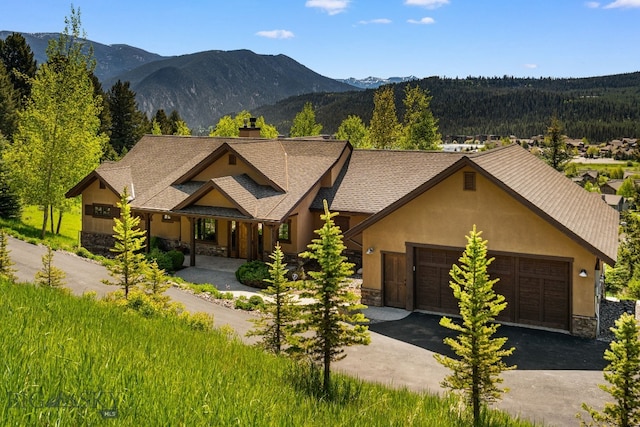 2430 Two Gun White Calf Rd, Big Sky, MT 59716 - view of front facade with stone siding, a garage, asphalt driveway, a chimney, and stucco siding