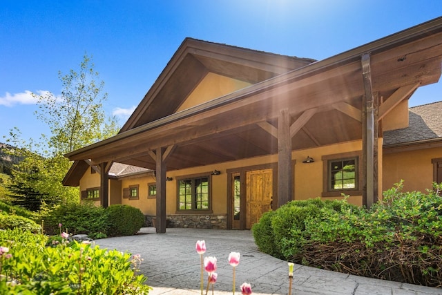 2430 Two Gun White Calf Rd, Big Sky, MT 59716 - entrance to property with stucco siding, a porch, and stone siding