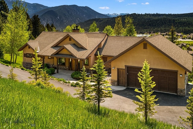 2430 Two Gun White Calf Rd, Big Sky, MT 59716 - view of front facade featuring stone siding, a chimney, stucco siding, and asphalt driveway