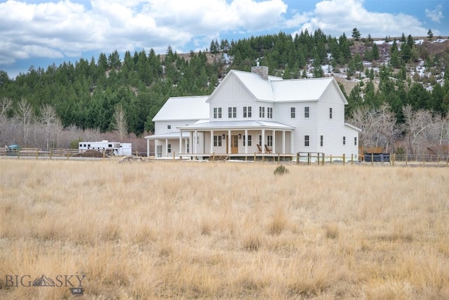 992 Deer Haven Dr, Deer Lodge, MT 59722 - back of property featuring covered porch, a chimney, and a view of trees