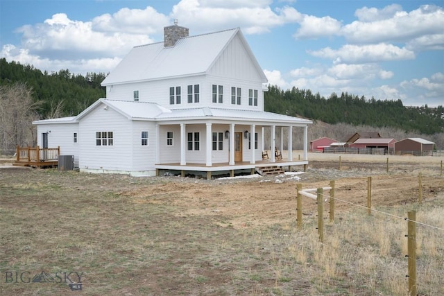 992 Deer Haven Dr, Deer Lodge, MT 59722 - rear view of house with central air condition unit, covered porch, a chimney, metal roof, and board and batten siding