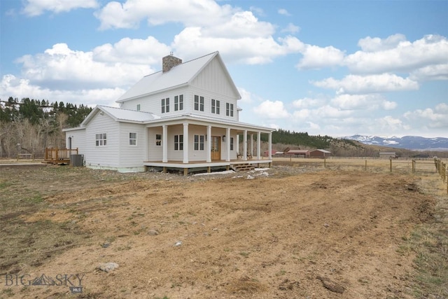 992 Deer Haven Dr, Deer Lodge, MT 59722 - rear view of property with covered porch, central air condition unit, metal roof, a chimney, and a mountain view