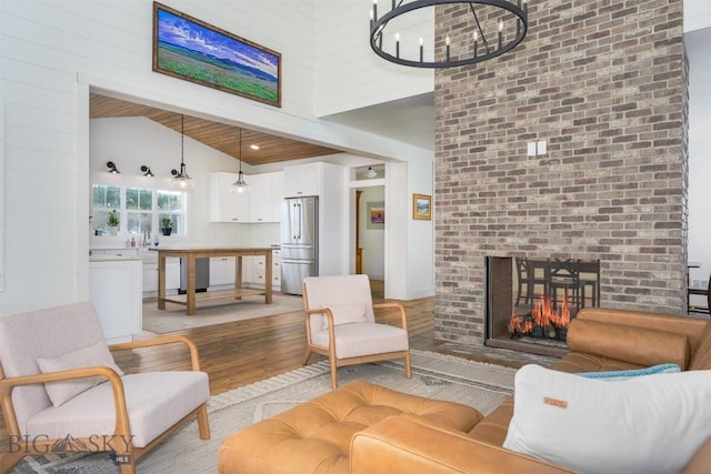 992 Deer Haven Dr, Deer Lodge, MT 59722 - living room with light wood-style flooring, a fireplace, high vaulted ceiling, and a chandelier
