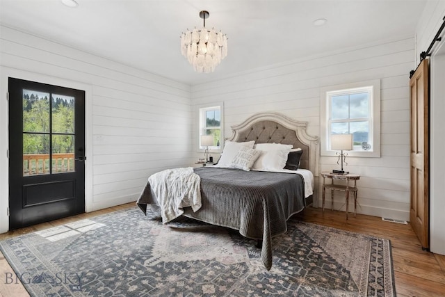 992 Deer Haven Dr, Deer Lodge, MT 59722 - bedroom featuring a barn door, multiple windows, a chandelier, and wood walls