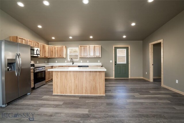 kitchen with stainless steel appliances, a center island, light brown cabinetry, vaulted ceiling, and light countertops