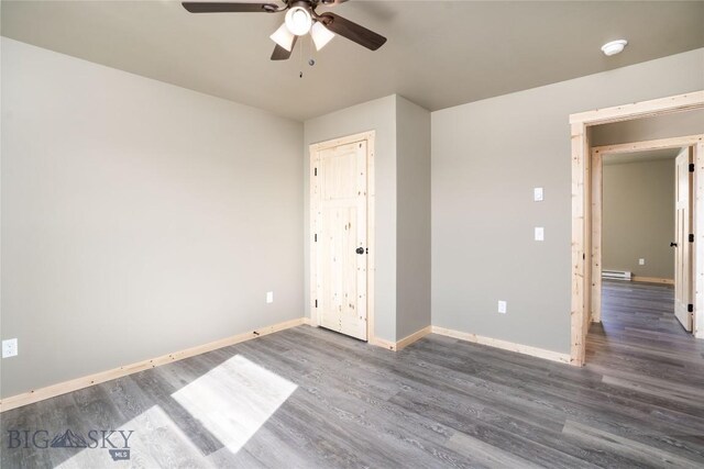 unfurnished bedroom with a baseboard heating unit, baseboards, wood finished floors, and ceiling fan