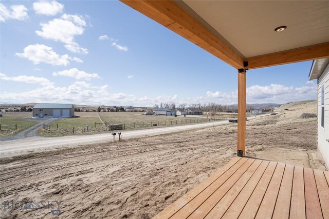 wooden terrace with a rural view and fence