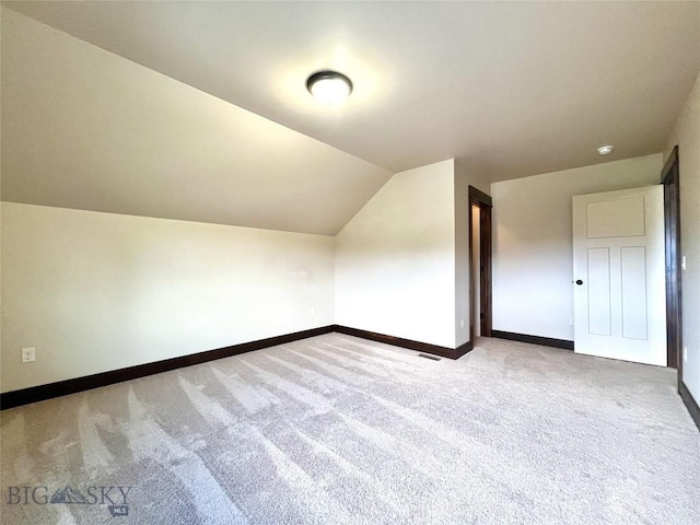additional living space with carpet floors, baseboards, and vaulted ceiling