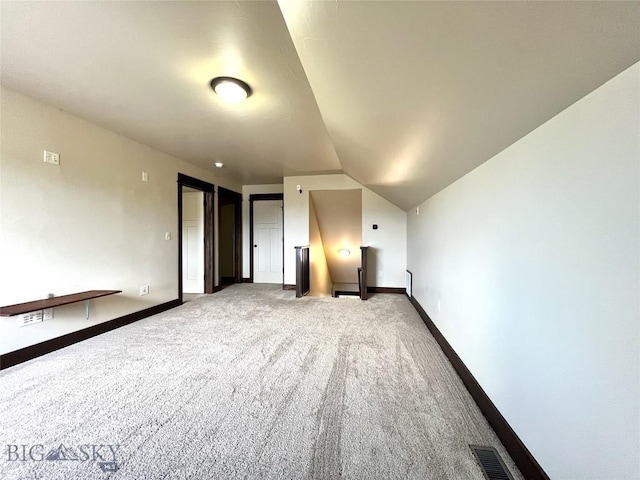additional living space with vaulted ceiling, baseboards, carpet, and visible vents