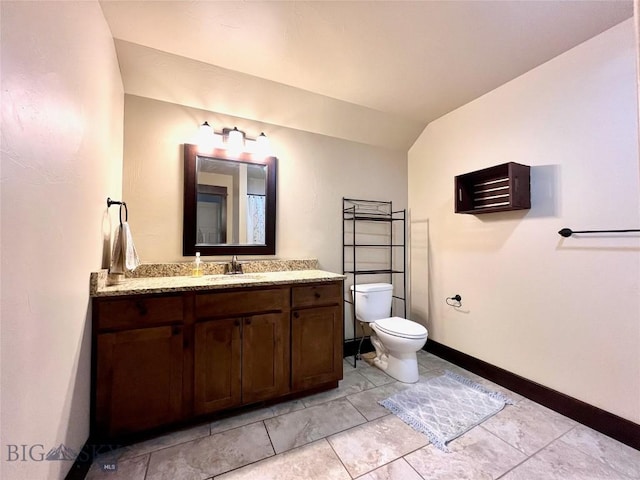 bathroom with vanity, baseboards, toilet, and lofted ceiling