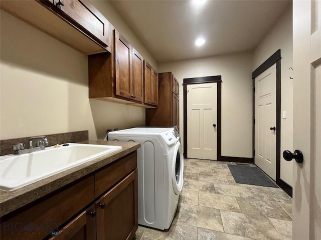 washroom with a sink, washer and clothes dryer, cabinet space, and stone finish floor