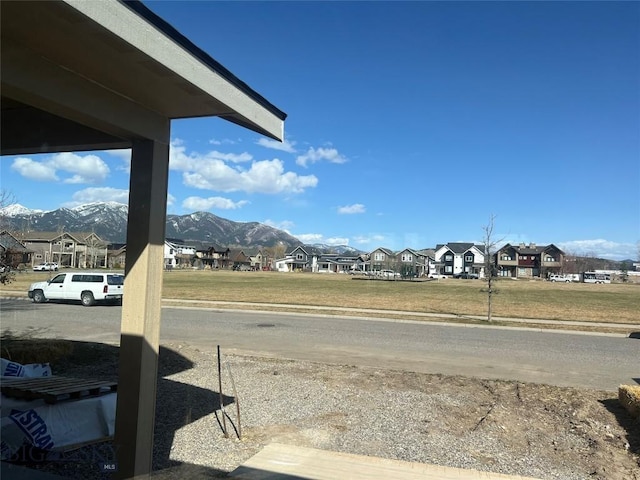 view of street with curbs, a residential view, a mountain view, and sidewalks