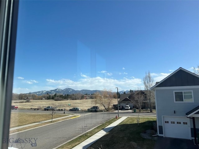 view of street with curbs, street lights, a mountain view, and sidewalks