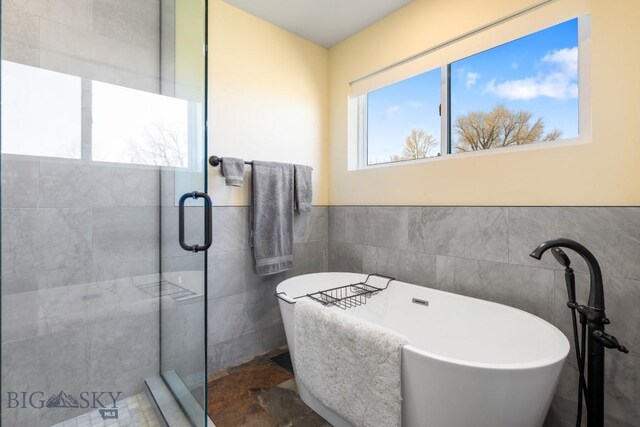 9 Cedar Ct, Ennis, MT 59751 - bathroom with tile walls, a soaking tub, a stall shower, and a wainscoted wall