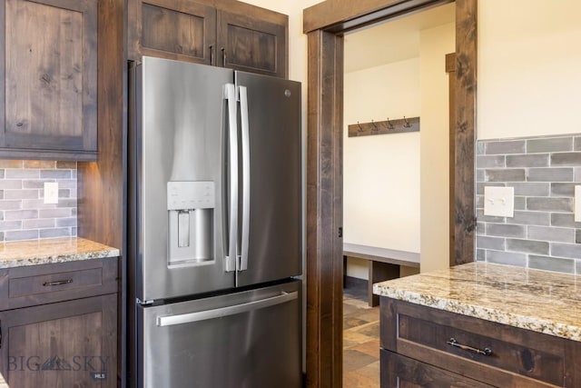 9 Cedar Ct, Ennis, MT 59751 - kitchen featuring stainless steel refrigerator with ice dispenser, backsplash, dark brown cabinetry, and light stone countertops