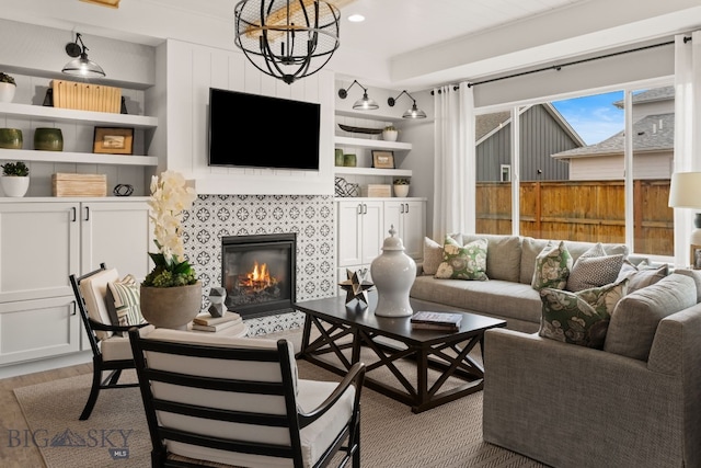living area featuring a chandelier, wood finished floors, a fireplace, and built in features
