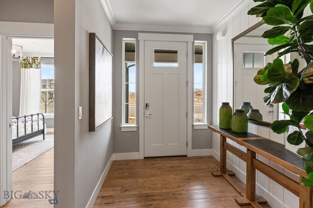 foyer featuring baseboards, an inviting chandelier, crown molding, and wood finished floors