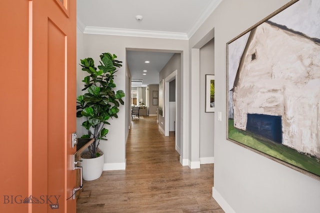 hall featuring crown molding, baseboards, and wood finished floors
