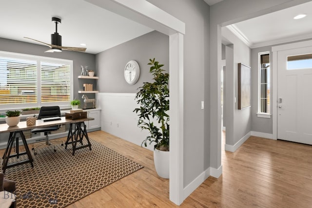 office area featuring a ceiling fan, ornamental molding, light wood-style flooring, and baseboards