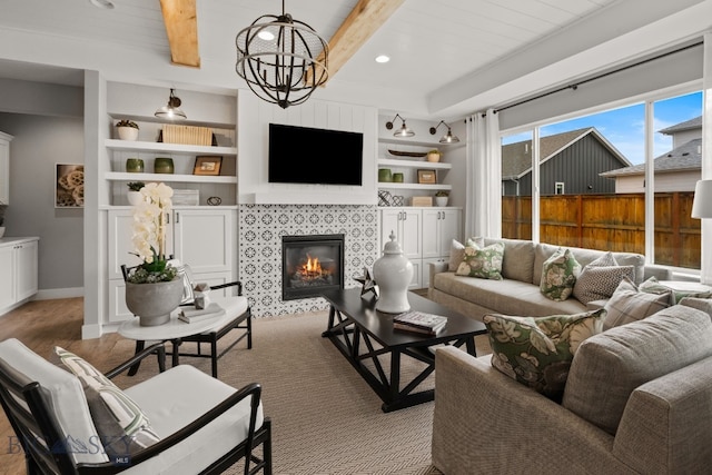 1516 Wild Bill Way, Belgrade, MT 59714 - living area featuring a tiled fireplace, wood finished floors, beamed ceiling, built in features, and baseboards