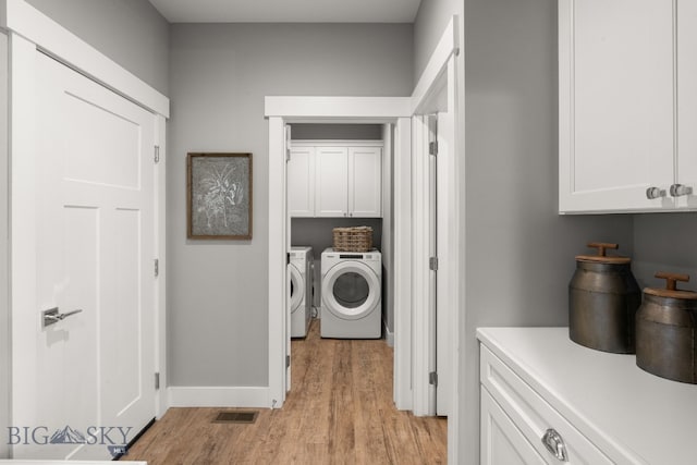laundry room featuring washer and dryer, cabinet space, light wood finished floors, and baseboards