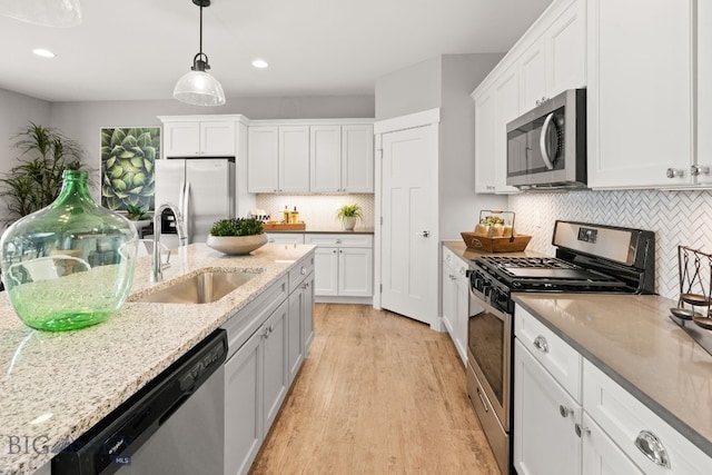 1516 Wild Bill Way, Belgrade, MT 59714 - kitchen with appliances with stainless steel finishes, a sink, light wood-style floors, white cabinetry, and recessed lighting