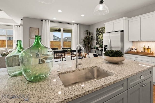 1516 Wild Bill Way, Belgrade, MT 59714 - kitchen featuring stainless steel fridge with ice dispenser, a sink, light stone counters, decorative backsplash, and recessed lighting