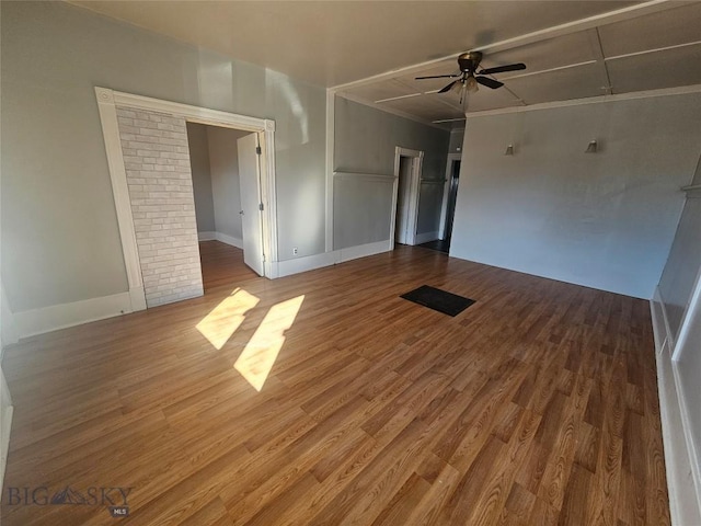 unfurnished room with wood finished floors, a ceiling fan, and baseboards