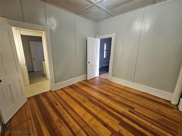 empty room with hardwood / wood-style flooring and a decorative wall