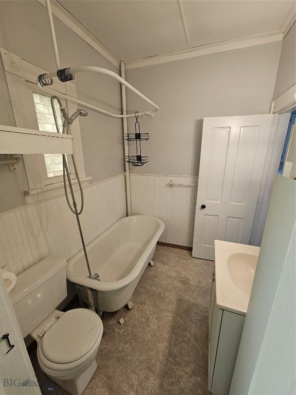 full bath with toilet, crown molding, and a wainscoted wall