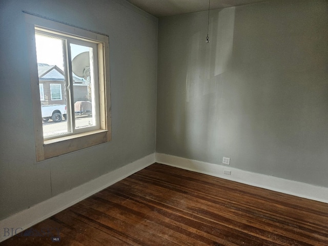 empty room featuring dark wood-type flooring, baseboards, and a healthy amount of sunlight