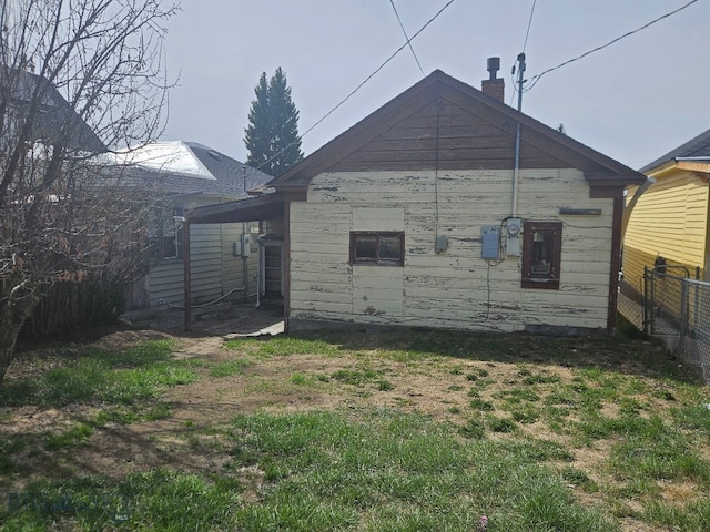 back of property with a chimney and fence