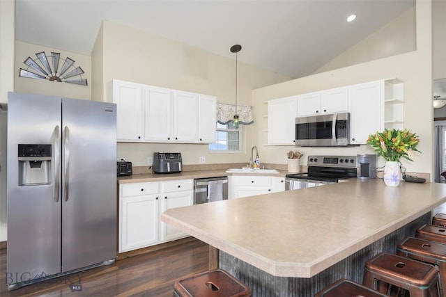 kitchen with white cabinets, open shelves, a sink, appliances with stainless steel finishes, and a peninsula