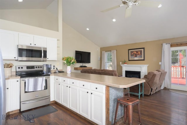 kitchen featuring dark wood finished floors, a peninsula, light countertops, stainless steel appliances, and open floor plan