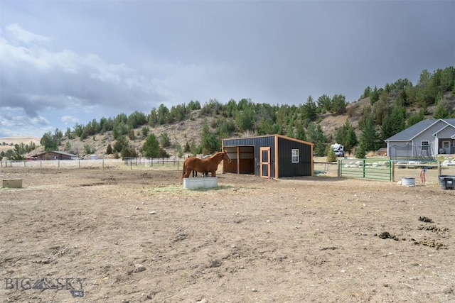 view of horse barn featuring a mountain view and a rural view