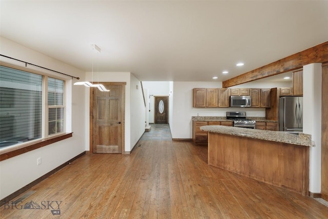 kitchen with a peninsula, baseboards, appliances with stainless steel finishes, and wood finished floors
