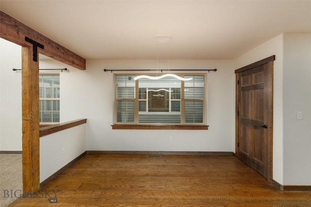 unfurnished dining area featuring baseboards, a chandelier, and wood finished floors