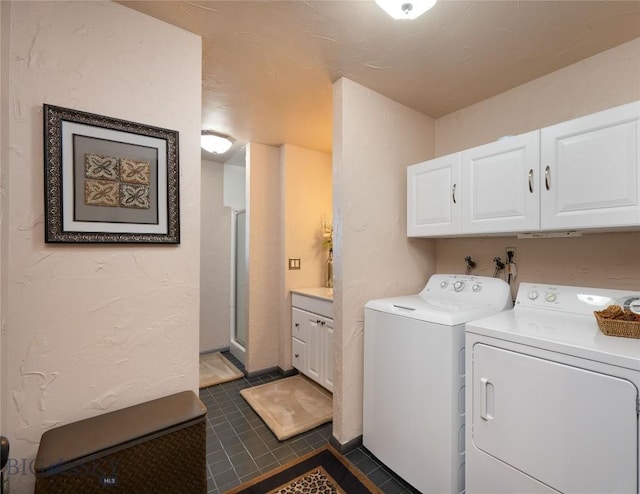 washroom with independent washer and dryer, dark tile patterned floors, and cabinet space