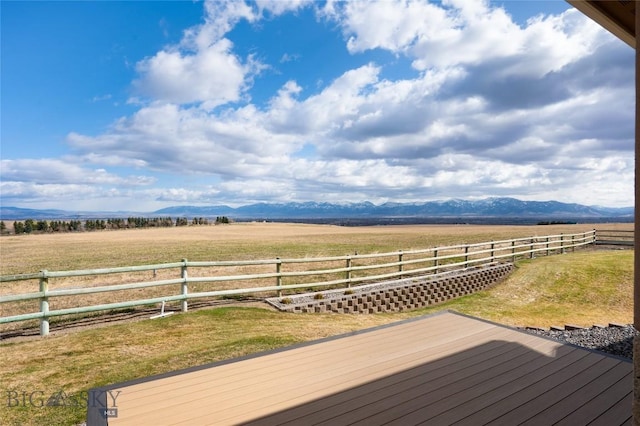 wooden terrace with a yard, a mountain view, fence, and a rural view