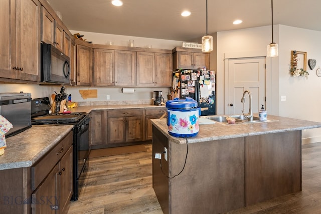 1519 Butler Crk Unit B, Belgrade, MT 59714 - kitchen featuring black appliances, a sink, wood finished floors, recessed lighting, and a kitchen island with sink