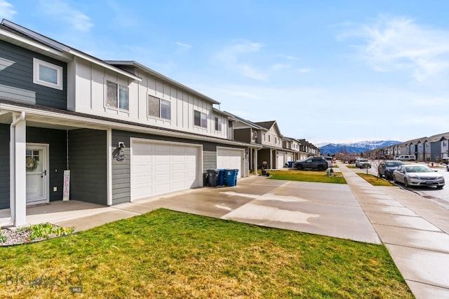 1519 Butler Crk Unit B, Belgrade, MT 59714 - view of side of home featuring board and batten siding, driveway, a mountain view, an attached garage, and a yard