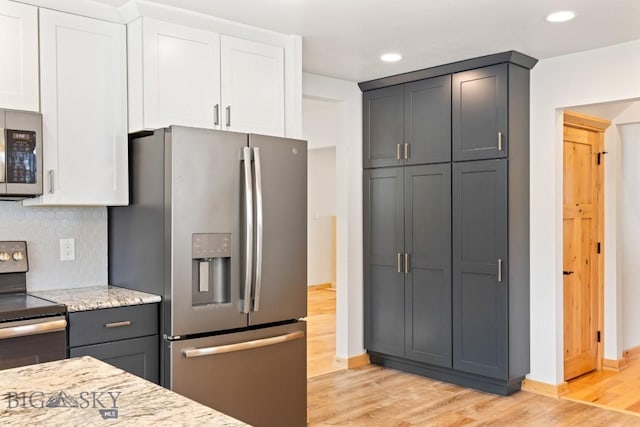 614 S 6th, Bozeman, MT 59715 - kitchen featuring light wood-style floors, light stone countertops, white cabinetry, appliances with stainless steel finishes, and baseboards
