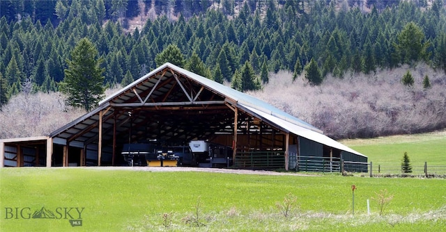 surrounding community with a view of trees, a detached carport, an exterior structure, and an outdoor structure